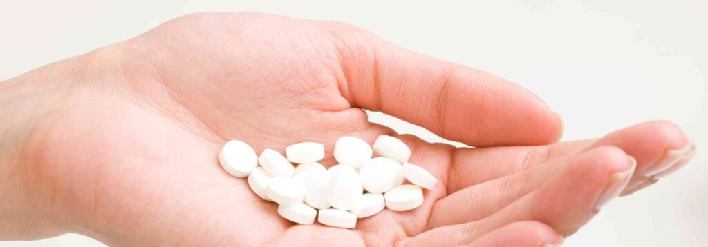 person holding white tablets in their hand