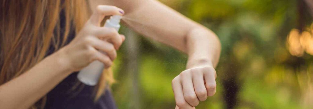 woman spraying insect repellent on her arm
