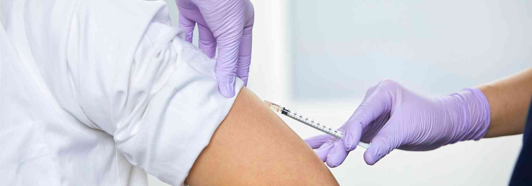 person in white shirt receiving vaccine from medical professional