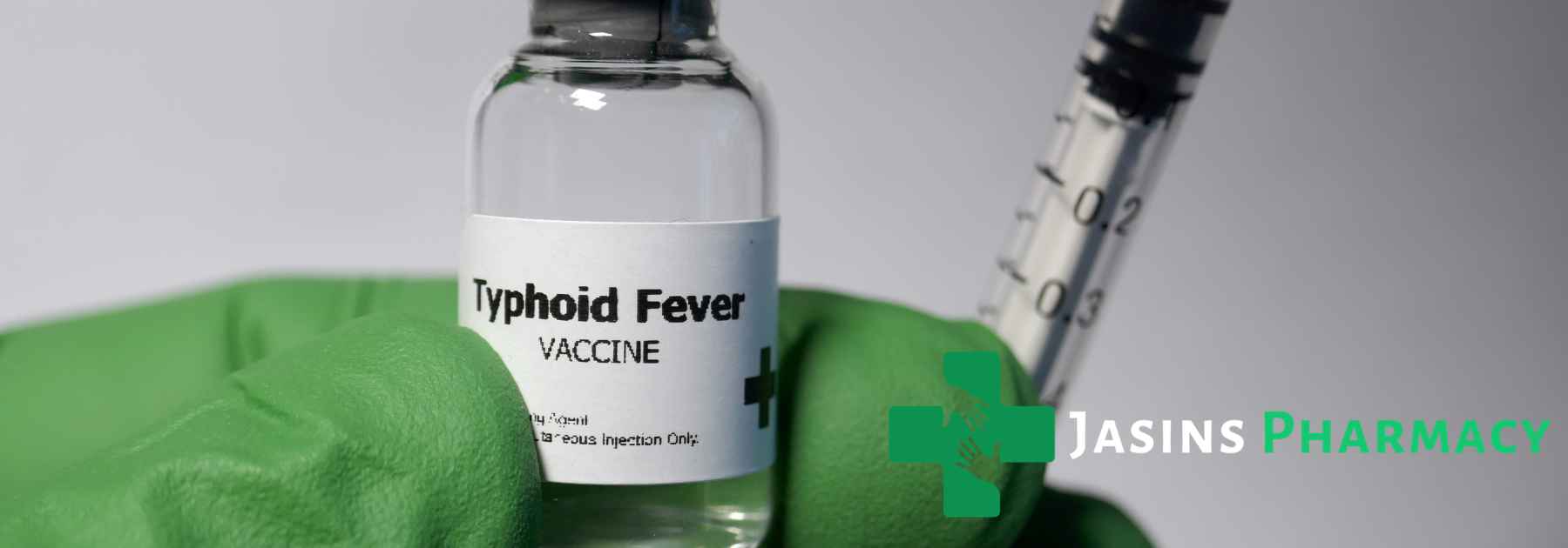 person wearing green medical glove holding typhoid vaccine