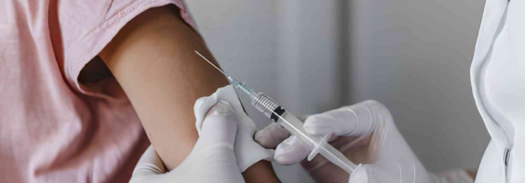 patient in pink shirt receiving vaccine in arm