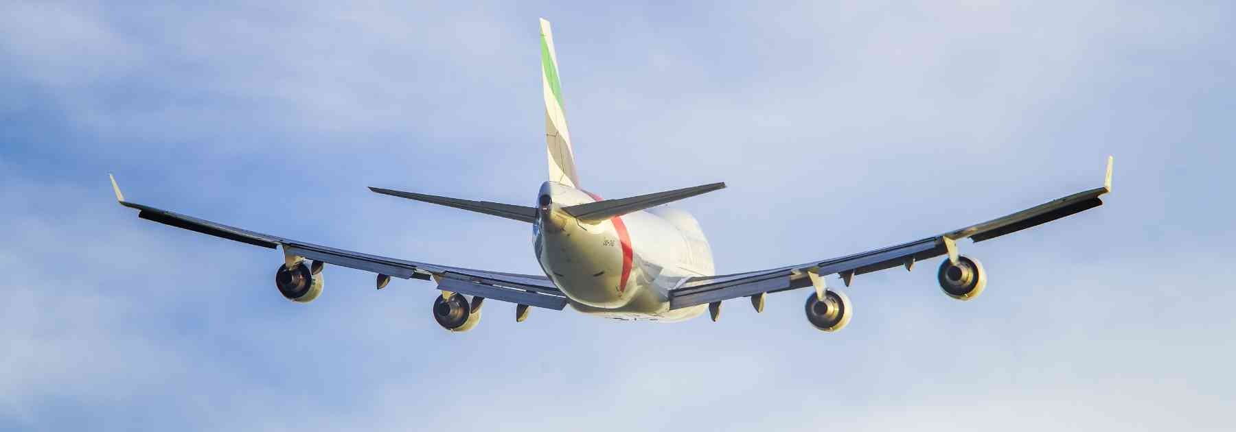 back view of plane flying in blue sky
