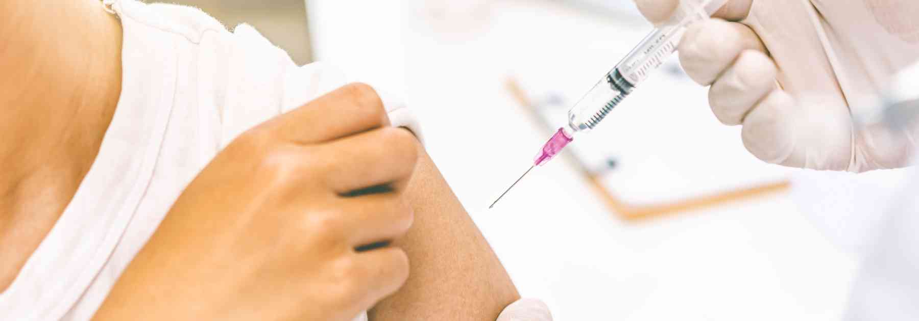 patient wearing white shirt receiving vaccine in arm