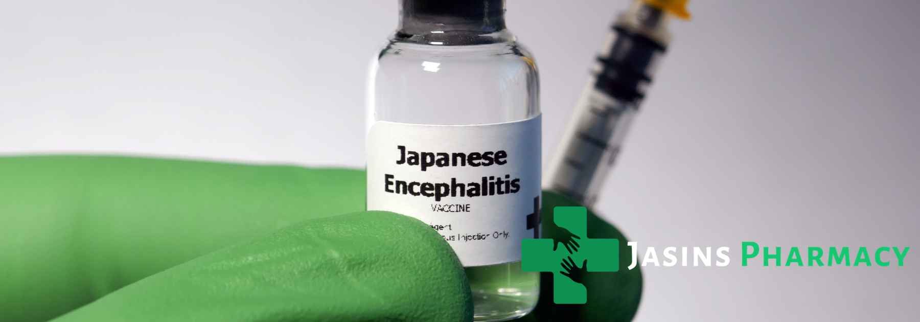 person wearing green medical glove holding japanese encephalitis vaccine